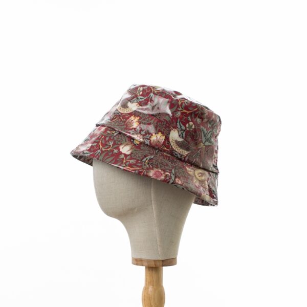 side view of a bucket rain hat in William Morris showerproof fabric. Willilam Morris Red ‘Strawberry Thief’ design which features thrushes and flowers on a deep red background