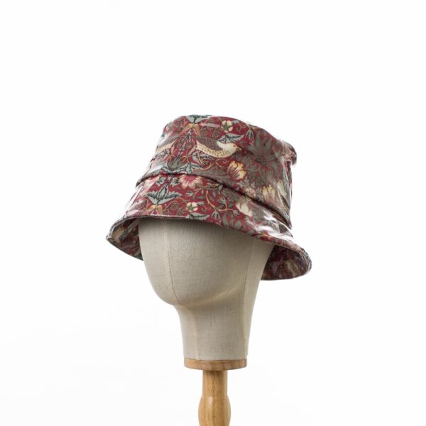 side view of a bucket rain hat in William Morris showerproof fabric. Willilam Morris Red ‘Strawberry Thief’ design which features thrushes and flowers on a deep red background.