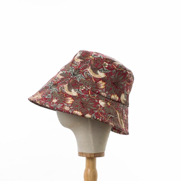 side view of Wide brimmed Sun Hat in licensed William Morris 100% cotton. Red ‘Strawberry Thief’ design fabric on a deep red background.
