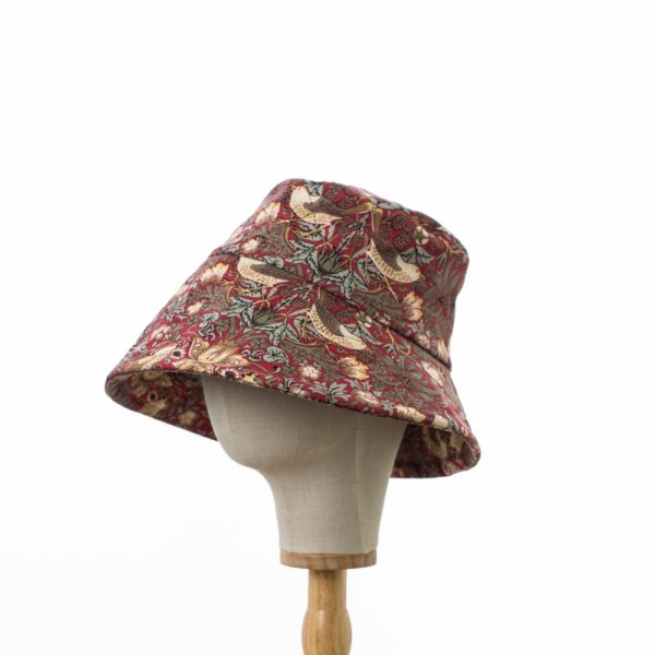 side view of a Wide brimmed Sun Hat in licensed William Morris 100% cotton. Red ‘Strawberry Thief’ design fabric on a deep red background.