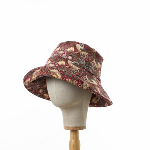 side view of a Wide brimmed Sun Hat in licensed William Morris 100% cotton. Red ‘Strawberry Thief’ design fabric on a deep red background.