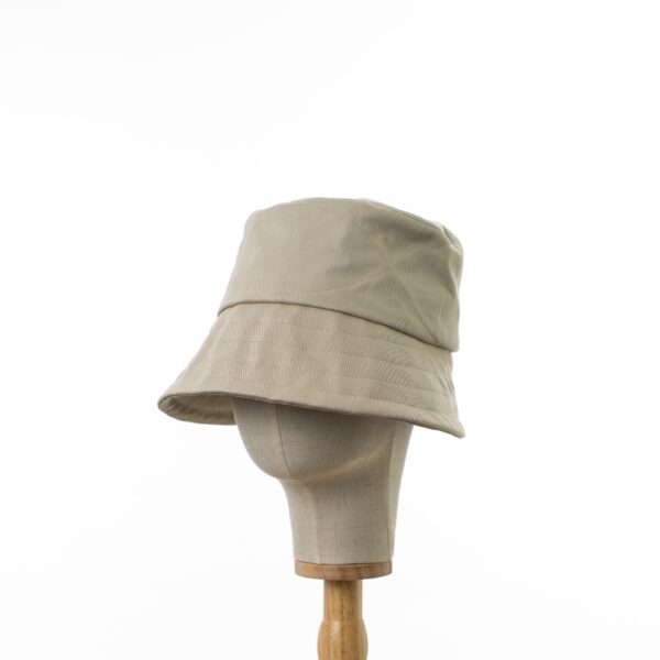 Chic Bayler and Co Bucket Hat made from 100% cotton beige drill fabric. Viewed in profile on a wooden and canvas hat stand