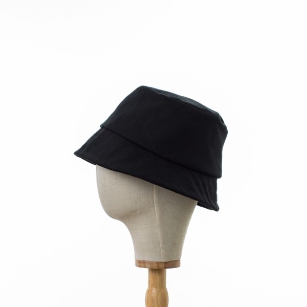 Classic Bayler and Co Bucket Hat made from 100% cotton black drill fabric. Displayed on a canvas and wooden hat stand on a white background. Profile view