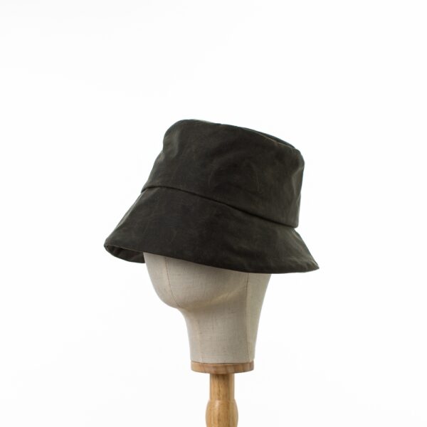 Chic and Practical Bayler and Co Dark Green shower proof bucket rain hat. Made from vintage look durable waxed cotton. displayed on a canvas and wooden hat stand on a white background.side on view