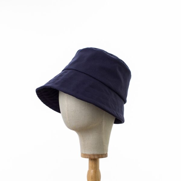 Chic Bayler & Co Bucket Hat made from 100% cotton navy drill fabric. Displayed on a canvas and wooden hat stand.slightly turned to the side.