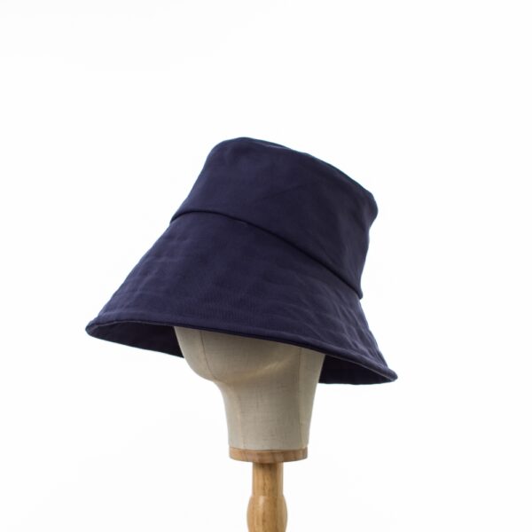 Elegant Bayler and Co wide brimmed Sun Hat made from 100% cotton navy drill fabric. The hat is displayed on a hat stand on a white background.