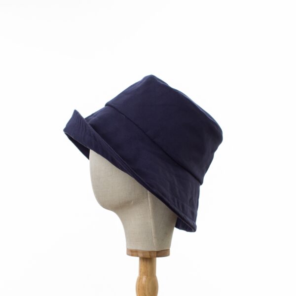 Elegant Bayler and Co wide brimmed Sun Hat made from 100% cotton navy drill fabric. The hat is displayed on a hat stand on a white background. Shows the hat with an upturned brim.