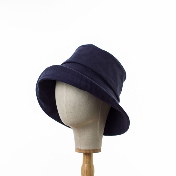 Elegant Bayler and Co wide brimmed Sun Hat made from 100% cotton navy drill fabric. The hat is displayed on a hat stand on a white background. Shows the hat with an upturned brim.
