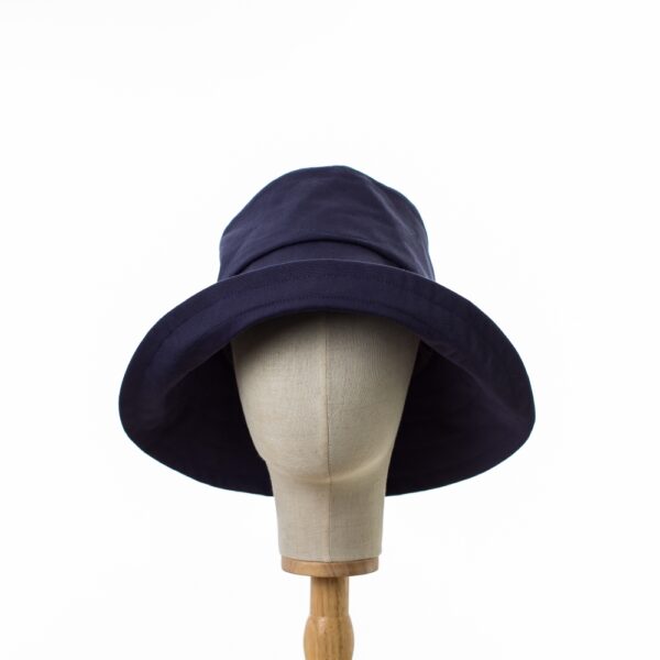 Elegant Bayler and Co wide brimmed Sun Hat made from 100% cotton navy drill fabric. The hat is displayed on a hat stand on a white background. Shows the hat with an upturned brim.