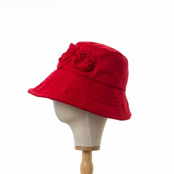 Elegant Bayler and Co wide brimmed Sun Hat with red roses made from 100% red cotton fabric. Viewed in profile displayed on a canvas and wooden hat stand.
