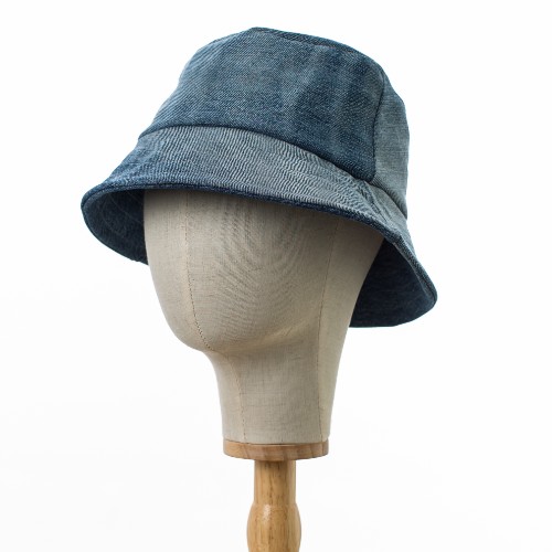 A side view of a Bayler and Co Upcycled Denim Bucket Hat. The hat is on a canvas hat stand and is slightly turned.